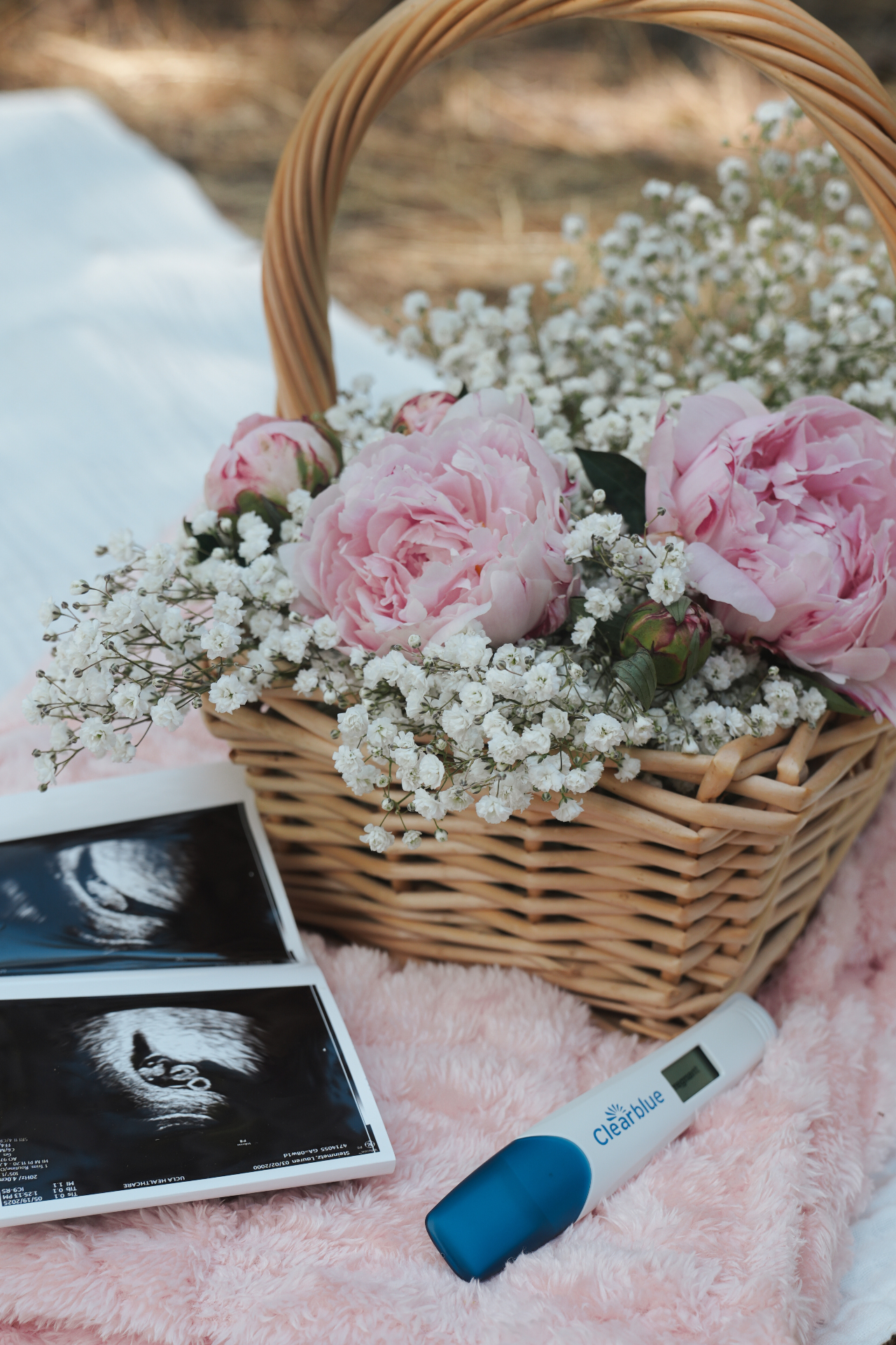 Wicker basket of soft pink peonies and baby's breath on a blush blanket