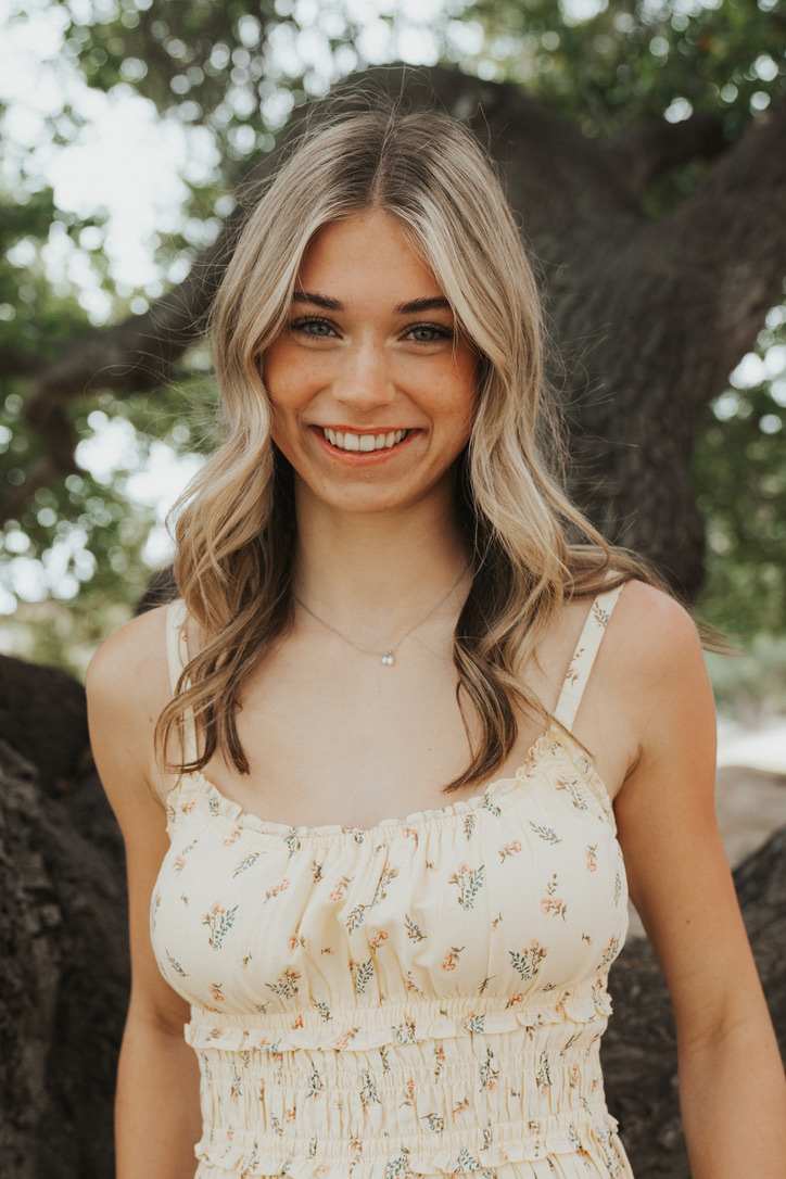 Close-up senior portrait smiling under oak branches
