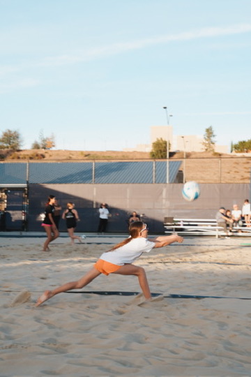 Beach volleyball player lunging for a dig at golden hour