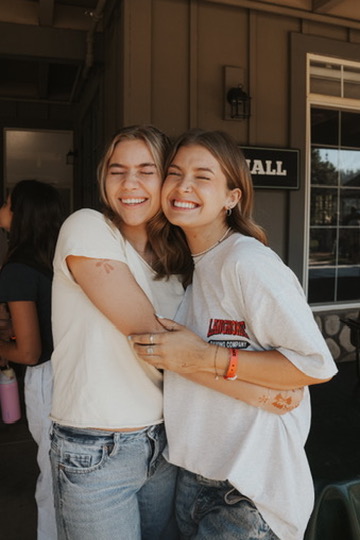Two friends hugging and laughing outside a cafe