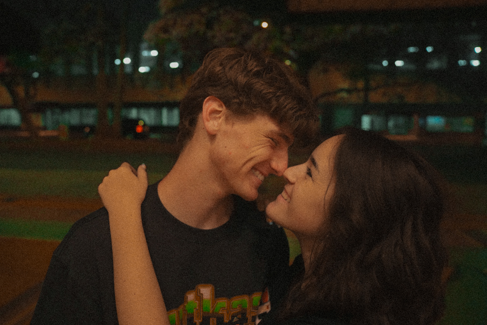 Couple laughing nose to nose under city lights at night