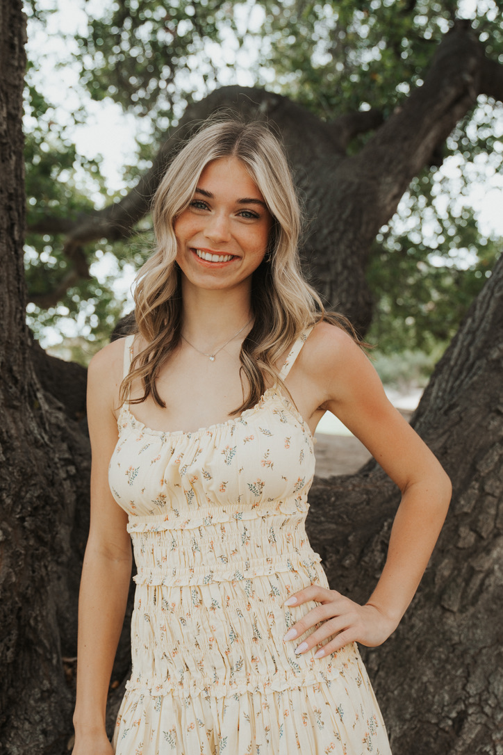Senior portrait in a floral dress in front of a sprawling oak