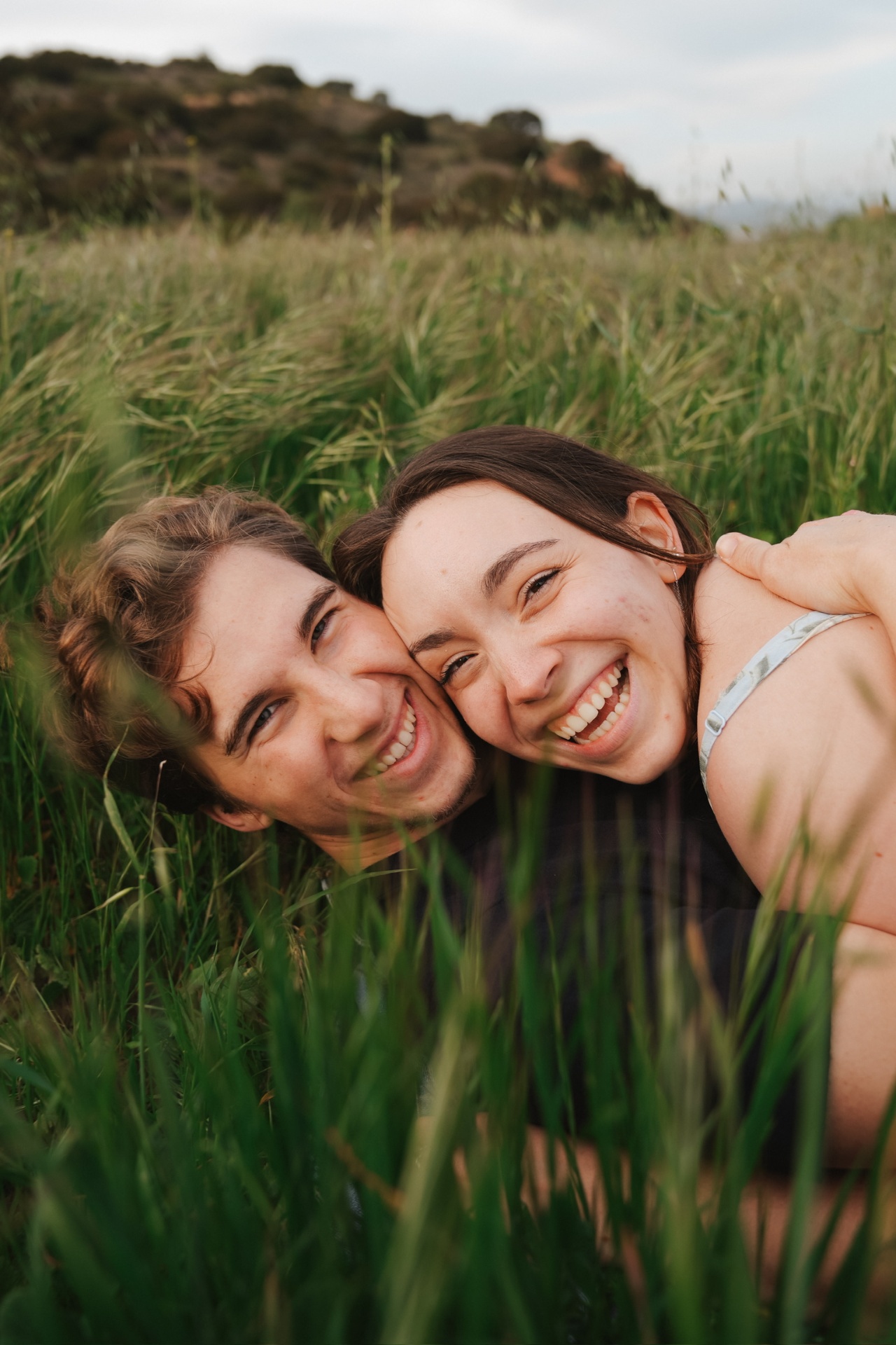 Cheek-to-cheek giggles lying low in tall green grass