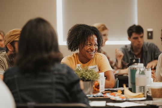 Woman laughing with friends around a table at a community event