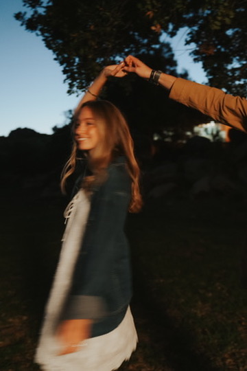 Woman twirling under her partner's hand at dusk