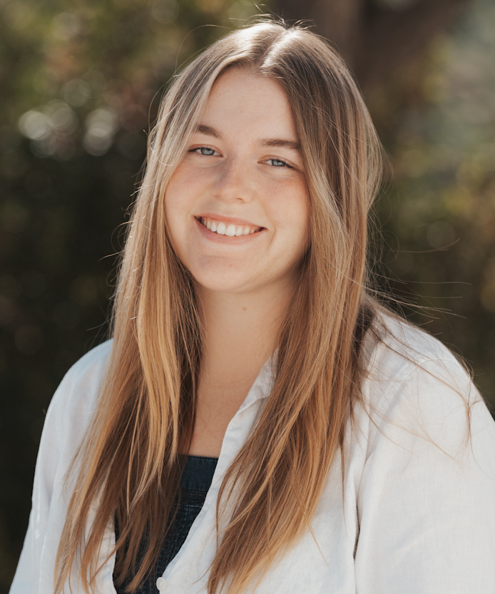 Sunlit headshot of a smiling woman in a white blouse