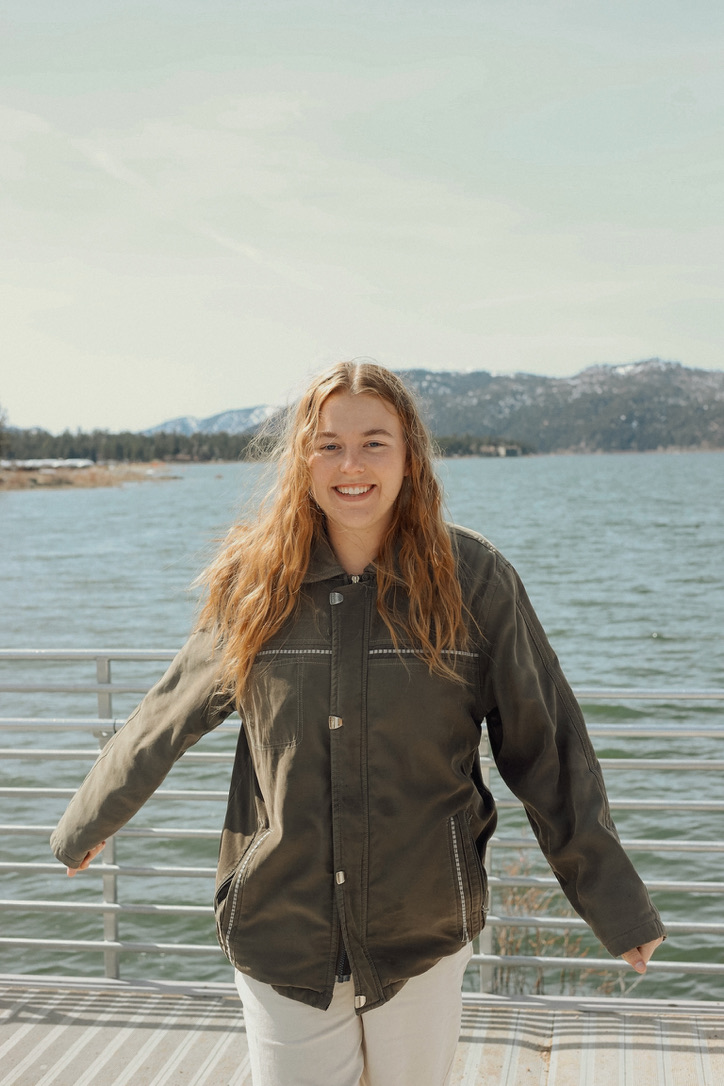 Woman smiling on a lakeside dock with mountains behind
