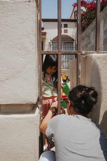Woman sharing a tender moment with a child through a gate in the sunshine