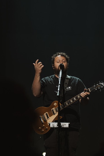 Guitarist singing on stage under moody concert lighting