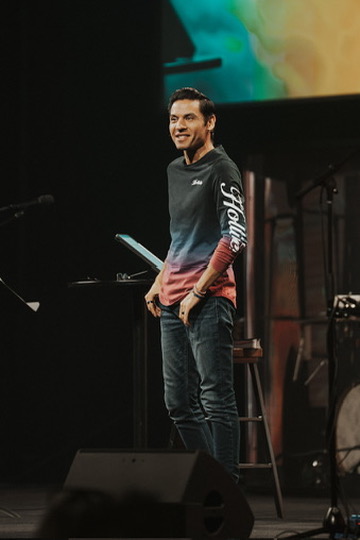 Speaker smiling on stage in front of a colorful backdrop