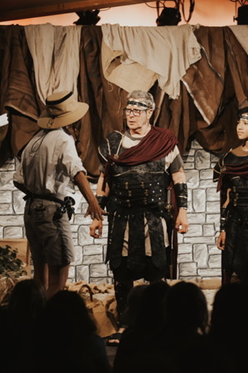 Theater performers in costume on a stone-wall stage set