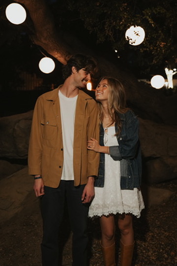 Couple smiling at each other under glowing lanterns at night