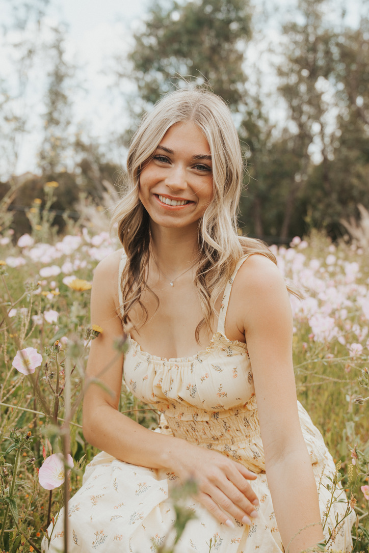 Senior portrait among pink wildflowers in a summer meadow