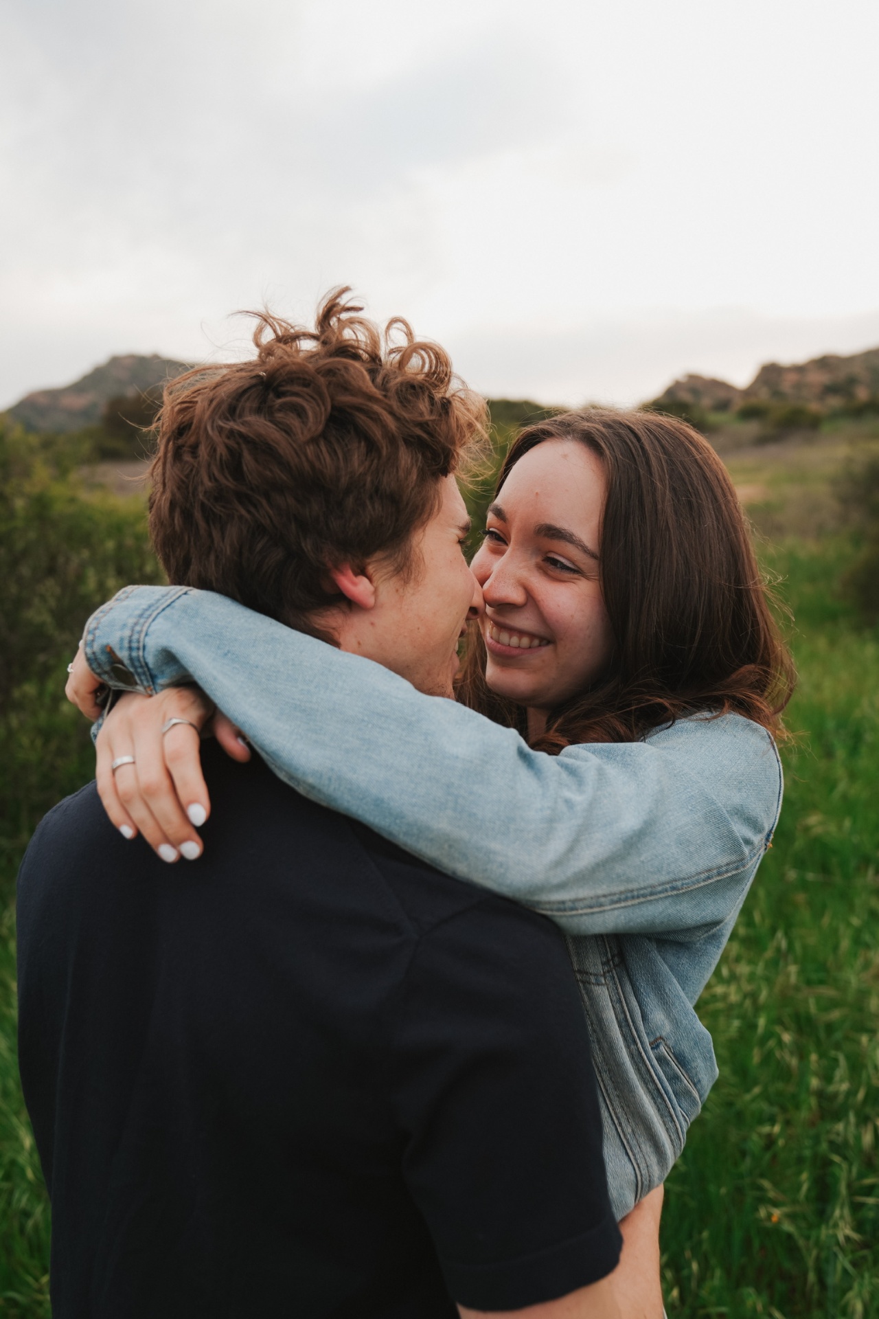 Nose-to-nose nuzzle and laughter wrapped in a denim-jacket hug
