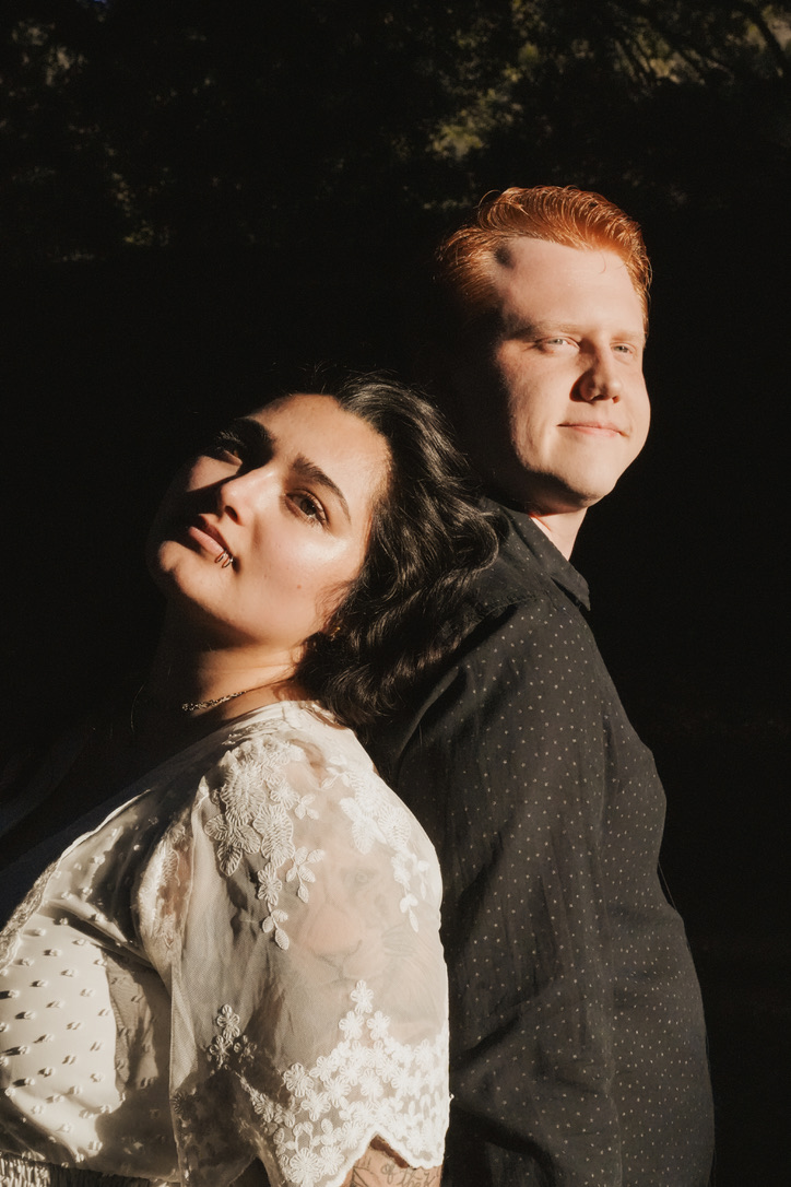 Sunlit back-to-back portrait of a couple against deep shadow