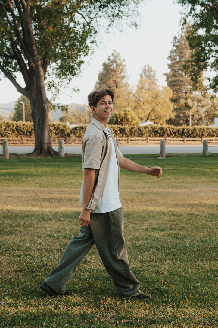 Mid-stride portrait walking across a sunlit park lawn