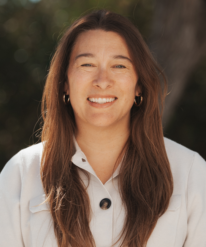 Warm outdoor headshot of a smiling woman with hoop earrings