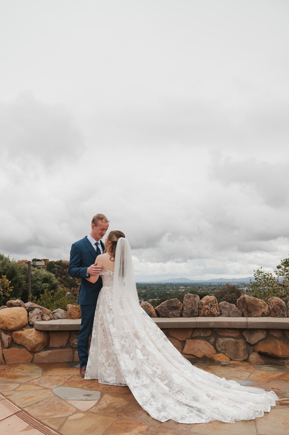 Bride and groom embracing on a hilltop overlooking the valley