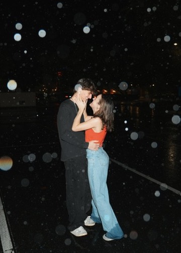 Couple sharing a kiss in the rain under city lights