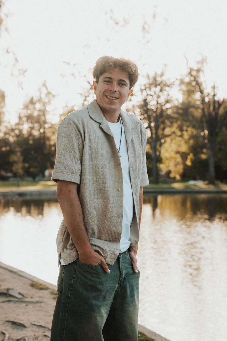Golden-hour lakeside portrait with hands in pockets