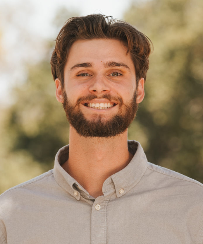Portrait of a smiling man in front of soft greenery