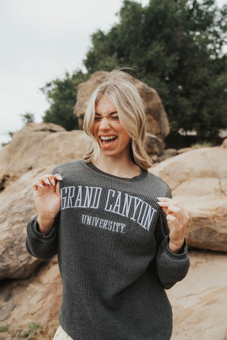 Grad laughing in a Grand Canyon University sweater by red rocks