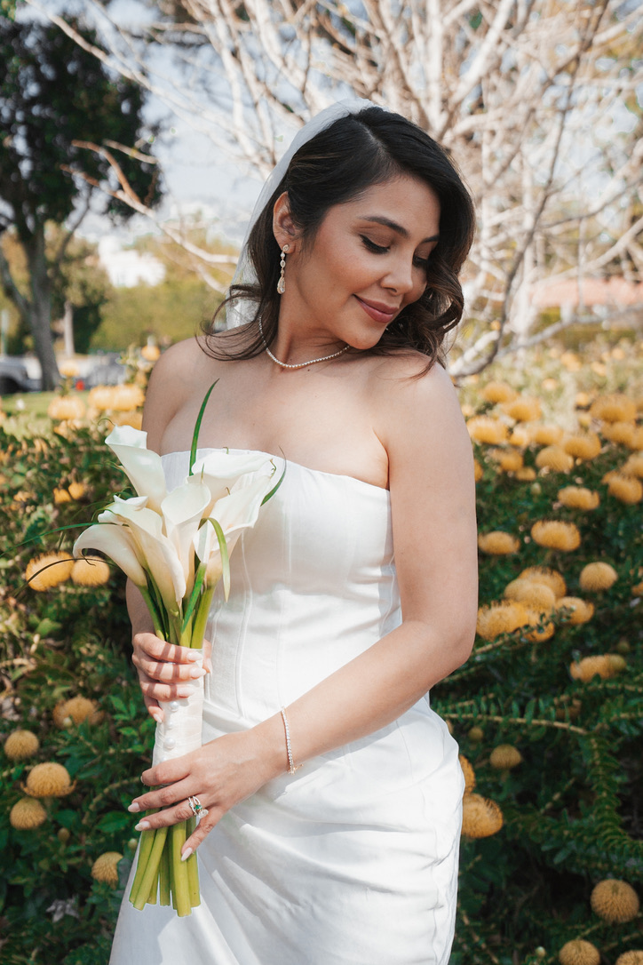 Bride with calla lily bouquet posing among golden blooms