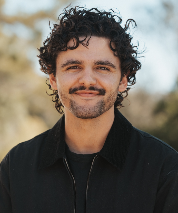 Outdoor headshot of a smiling man with curly hair