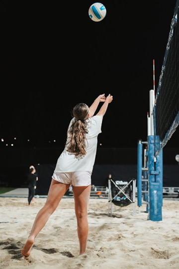 Beach volleyball player setting the ball under the night lights