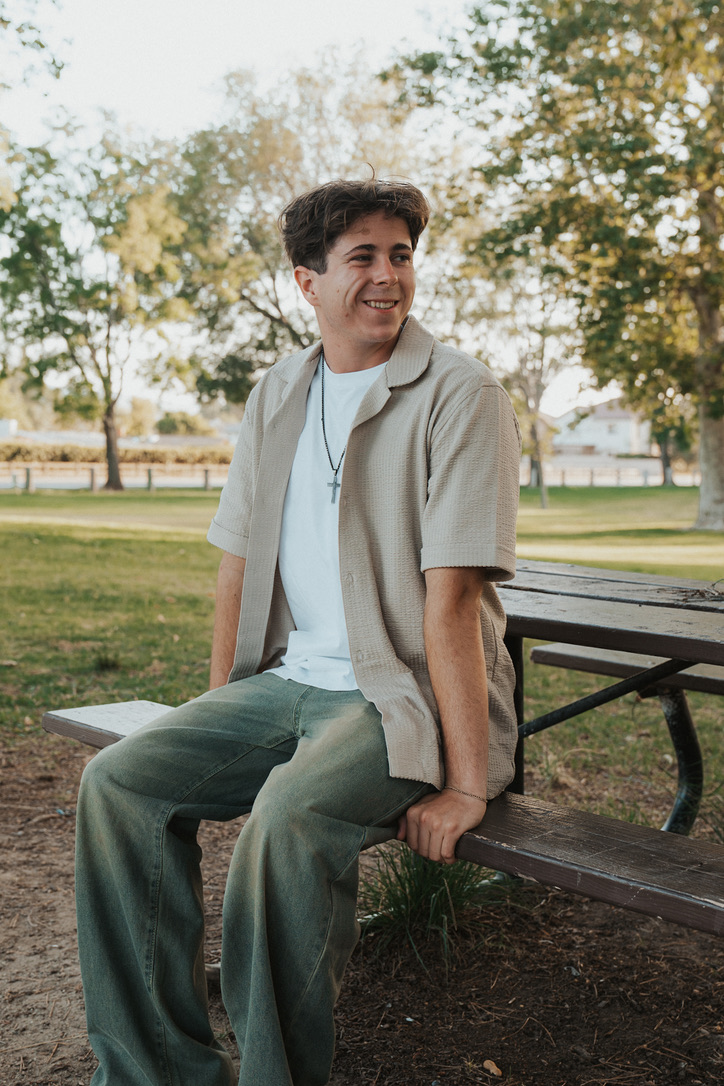 Relaxed portrait perched on a park picnic bench glancing away
