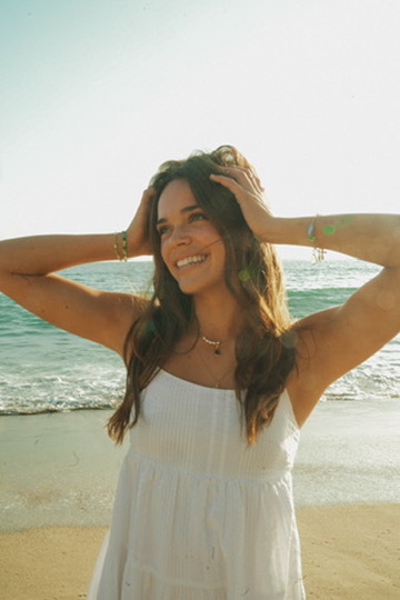 Woman in a white dress smiling on the beach in sunlit haze